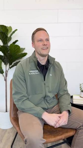 Dr. Bradley Brunner seated in a bright consultation room, mid-conversation.